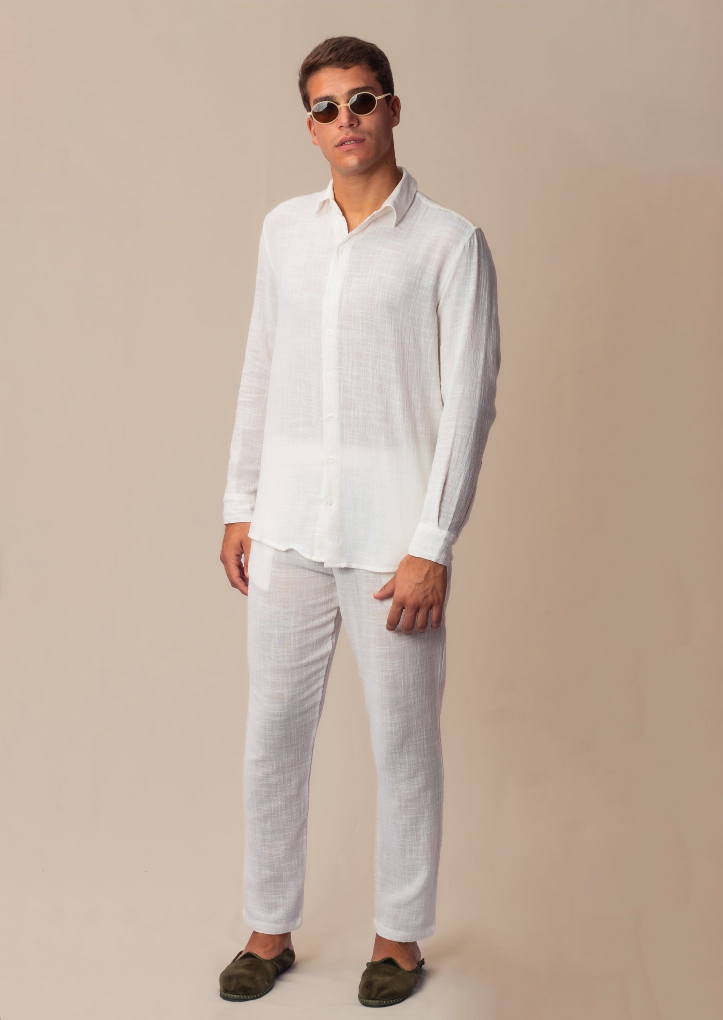 Vista lateral do full look com camisa manga longa e calça branca unissex em modelo masculino.