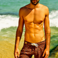 Modelo usando Board Shorts Paixão Nacional na praia, marrom e verde