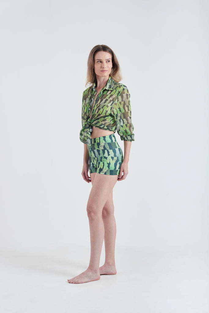 Modelo usando a Camisa Verde com estampa Olha o Custo, feita em tule, com hot pants