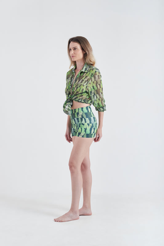 Modelo usando a Camisa Verde com estampa Olha o Custo, feita em tule, com hot pants