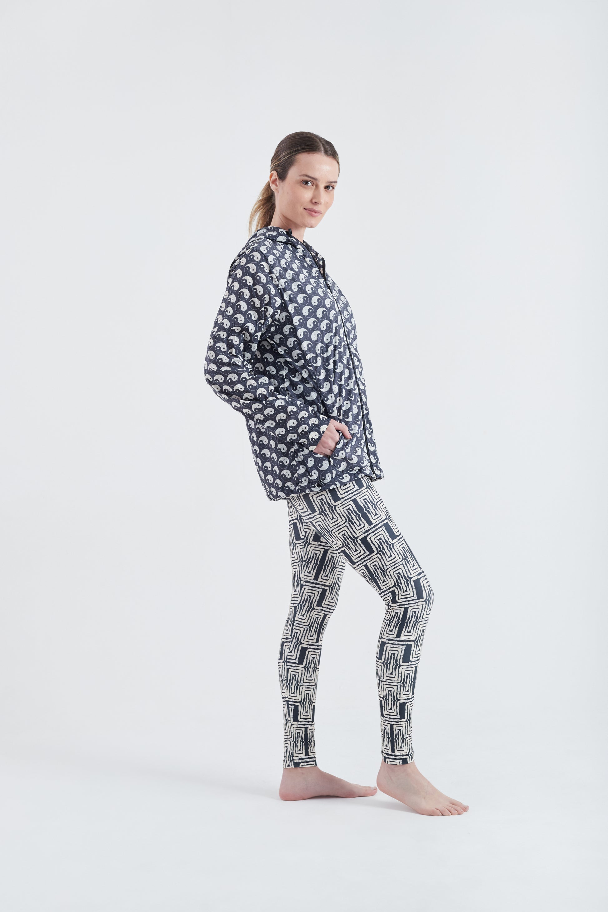 Modelo usando o corta vento unissex Yin and Out preto/branco, com calça Legging.
