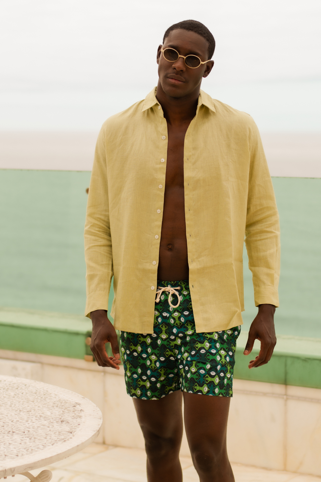 Modelo usando o shorts masculino verde Beijoqueira, com camisa de Linho.