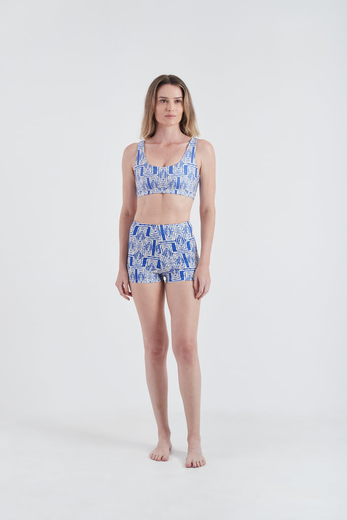 Modelo usando top + hot pants femininos azul/branco em lycra com estampa Mão Pela Perna.