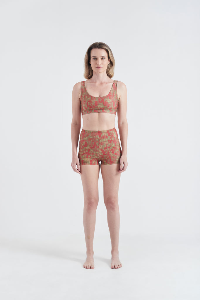 Modelo usando o conjunto top e hot pants vermelho/amarelo Mão Pela Perna