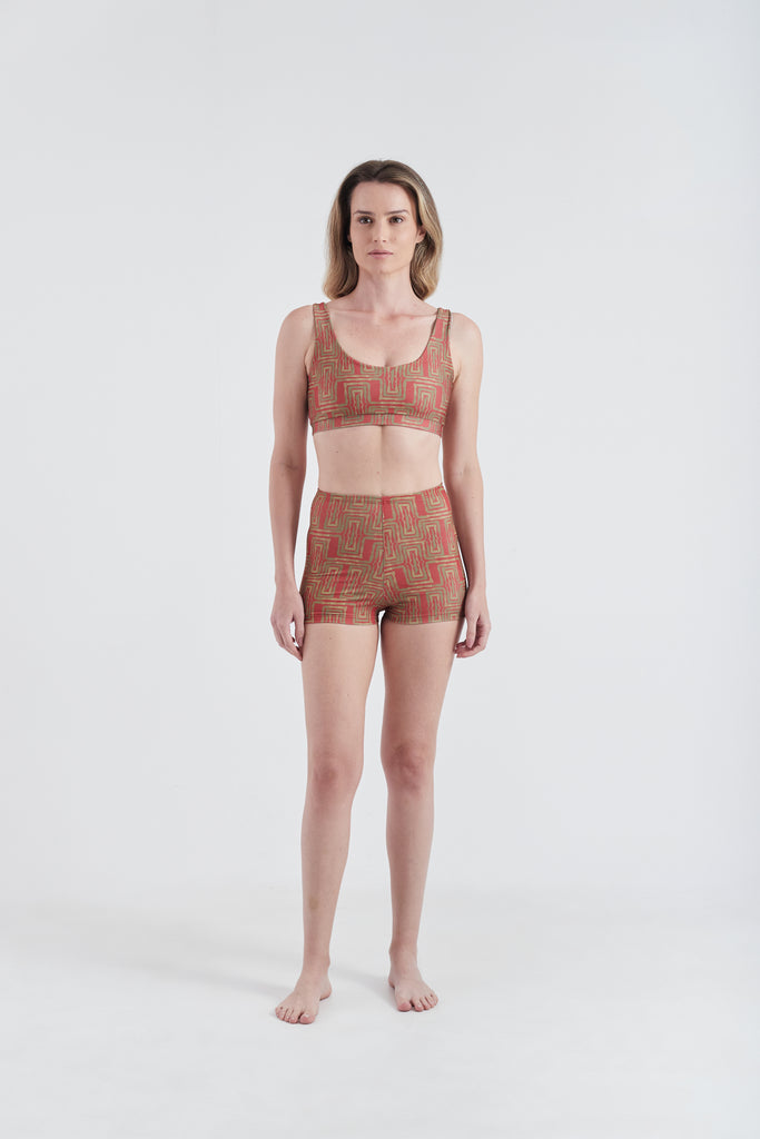 Modelo usando o conjunto top e hot pants vermelho/amarelo Mão Pela Perna, feito em  Lycra