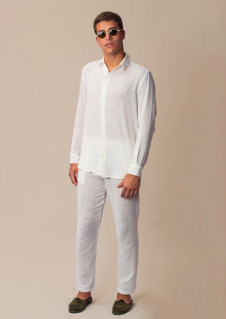 Vista lateral do full look com camisa manga longa e calça branca unissex em modelo masculino.