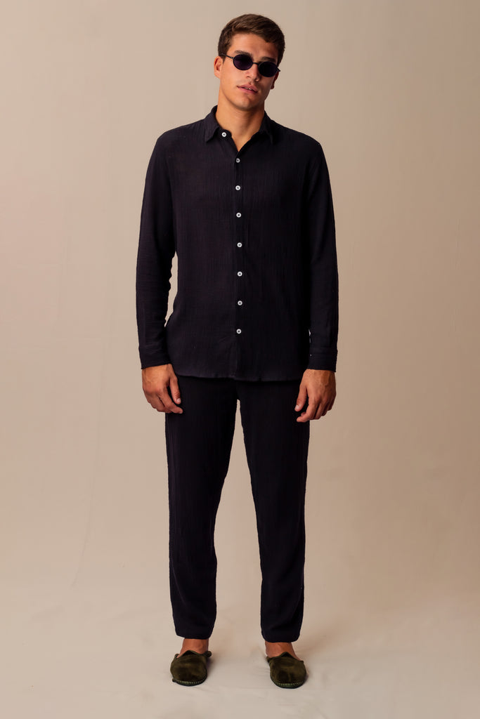 Modelo masculino vestindo full look com camisa manga longa e calça preta unissex, ideal para eventos e viagens.