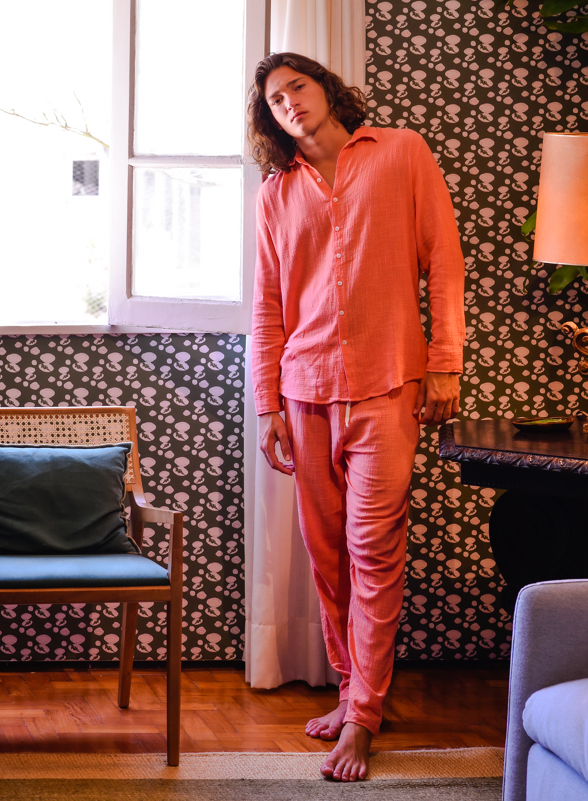 Modelo usando o conjunto Full Look Guava, camisa manga longa e calça, de pé ao lado de uma janela.