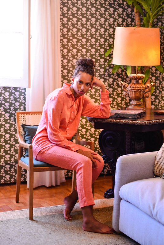 Camisa manga longa e calça Full Look Guava em tom vibrante de goiaba, modelo sentado em ambiente casual.