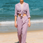 Modelo esbanjando estilo na praia com o Full Look Lavanda, camisa de manga longa e calça comfy.