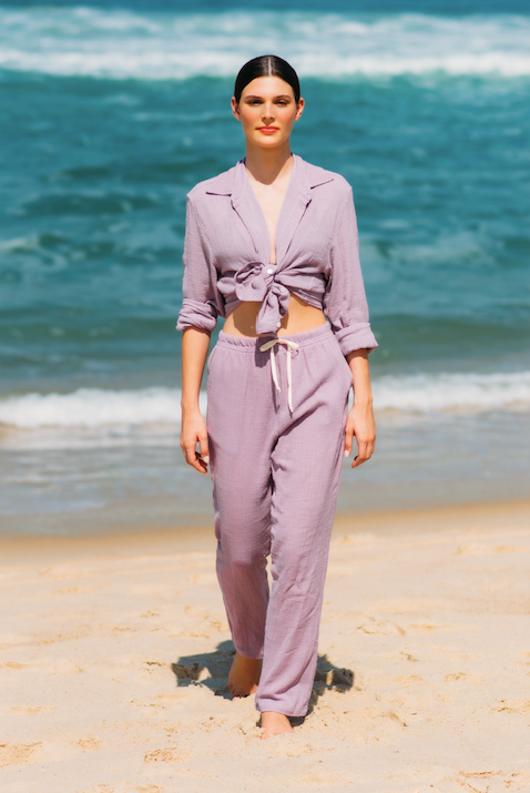 Modelo esbanjando estilo na praia com o Full Look Lavanda, camisa de manga longa e calça comfy.