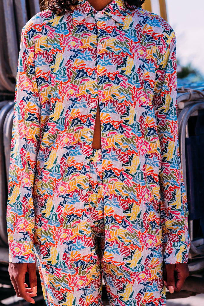 Detalhe da estampa Tan-Orexia Rainbow em camisa de manga longa, com padrão de mulheres relaxando ao sol.