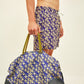 Vista lateral do Shorts Banana Chiquita Azul com modelo segurando uma bolsa combinando.