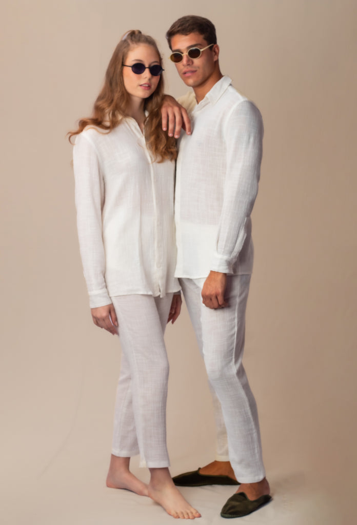 Modelo masculino e feminina vestindo full look com camisa manga longa e calça branca unissex, em ambiente de estúdio.